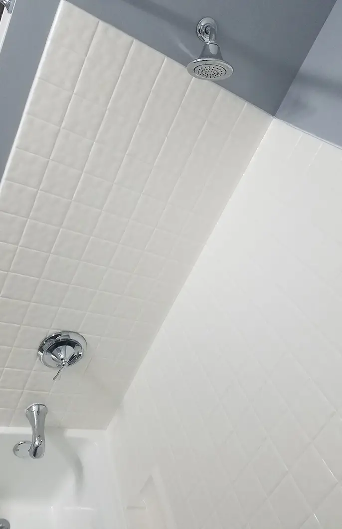 A shower with white tiling and a steel faucet