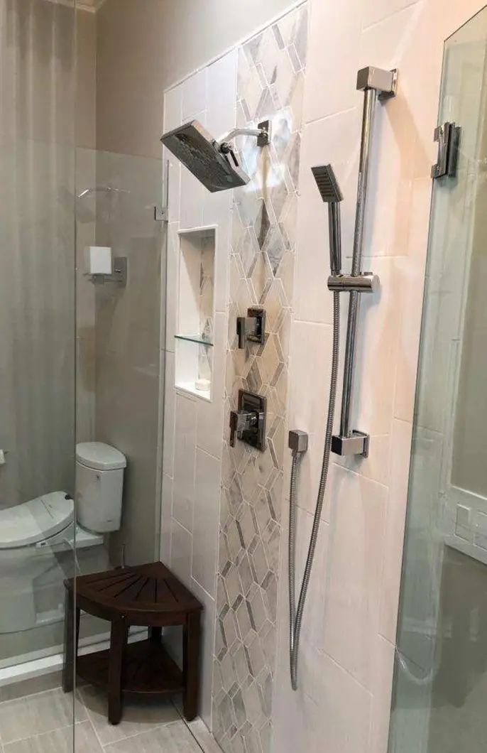 A newly installed showerhead and toilet in a renovated bathroom