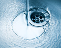 Water pouring down stainless steel kitchen sink drain