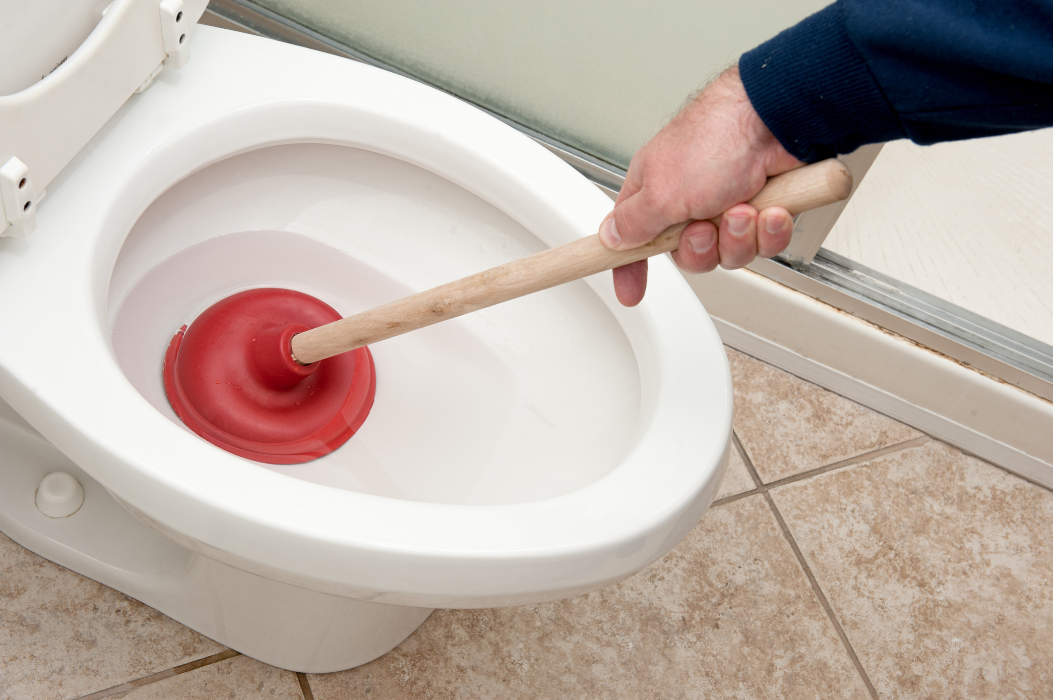 Plumber unclogging toiler using plunger
